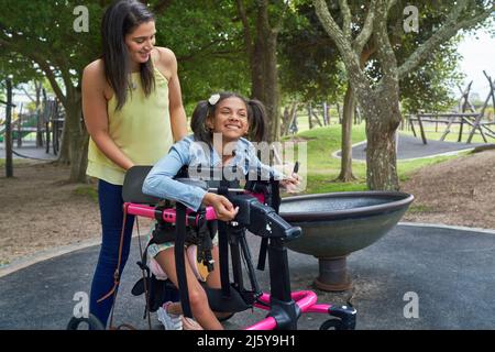 Mother and happy disabled daughter in rollator at park Stock Photo