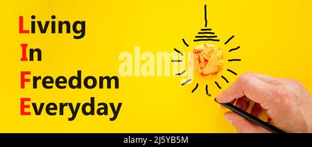LIFE living in freedom everyday symbol. Concept words LIFE living in freedom everyday on beautiful yellow background. Businessman hand. Business LIFE Stock Photo