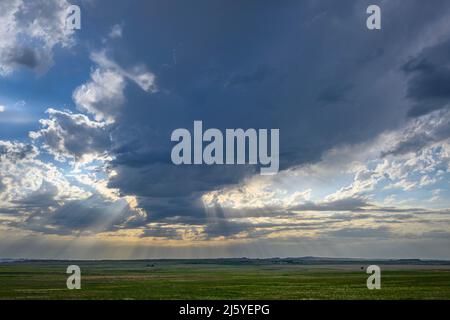Crepsucular rays and storm clouds over the prairie in Badlands National Park, South Dakota Stock Photo