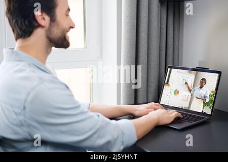 Virtual conference. Young man using pc for video call, having video meeting with his multiracial colleague together. Remote work concept Stock Photo