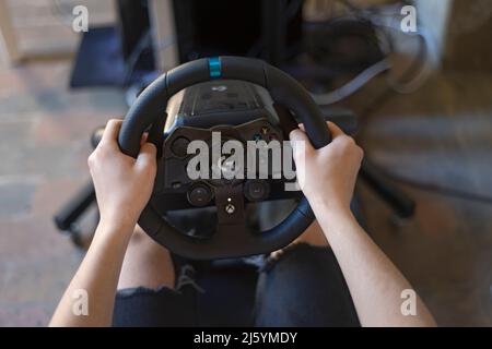 Hands of a Boy on a Steering Wheel, While he Plays a Racing Game Stock Photo