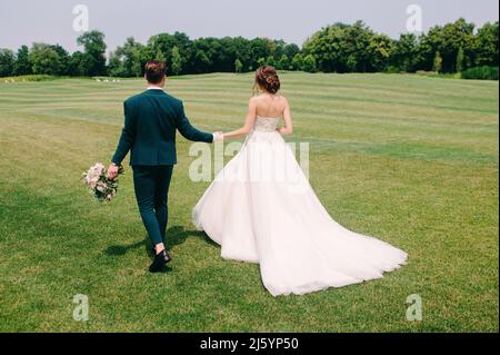 Summer wedding. Bride and groom walking outdoor. Portrait of happy beautiful newlyweds walking in the park Stock Photo
