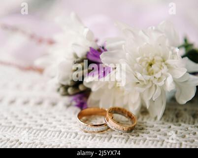 Wedding rings/band with floral decorations, on vintage knitted napkin, two golden rings. Country wedding in retro style Stock Photo