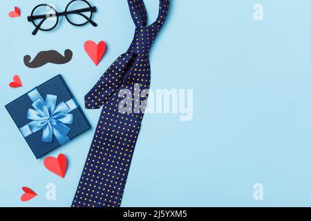 Father's day composition. Gift tie glasses mustache red hearts on a blue background. Stock Photo