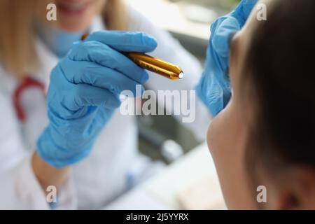 Doctor neurologist shining flashlight on patient eyes in clinic closeup. Diagnosis of neurological diseases of brain concept Stock Photo