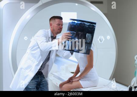 Doctor showing patient mri scan of spine in clinic. Modern methods of examination and diagnosis of diseases of nervous system concept Stock Photo