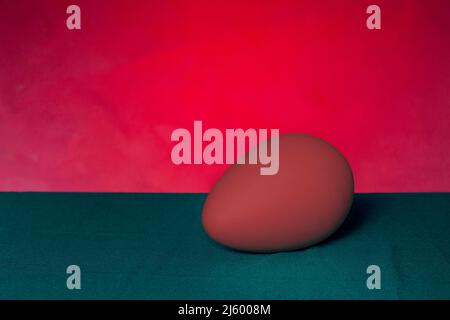 Red egg on green table and red background.  Stock Photo