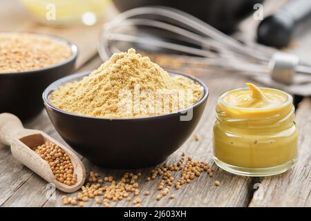 Mustard sauce jar and bowl of powdered mustard seeds. Scoop of whole mustard grain. Stock Photo