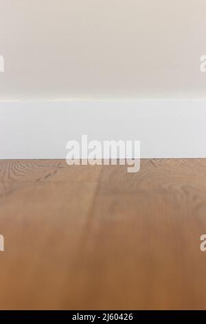 White baseboard, white wall and wood laminate. Stock Photo