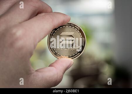 Solana SOL cryptocurrency physical coin held between two fingers. Stock Photo