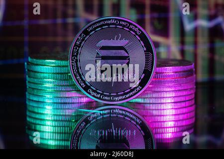 Solana SOL cryptocurrency physical coin and blurry price charts. Stock Photo