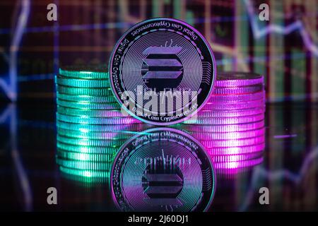 Solana SOL cryptocurrency physical coin and blurry price charts. Stock Photo