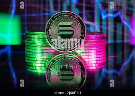 Solana SOL cryptocurrency physical coin and blurry price charts. Stock Photo