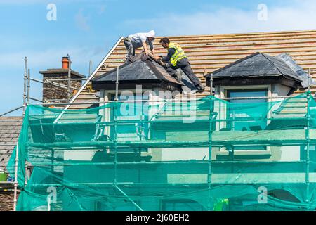 Roofers on scaffolding tiling a domestic roof in Dingle, County Kerry, Ireland. Stock Photo