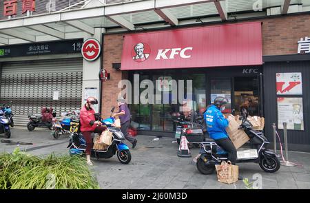 SHANGHAI, CHINA - APRIL 26, 2022 - Deliverymen work at the gate of KFC on April 26, 2022 in Shanghai, China Stock Photo