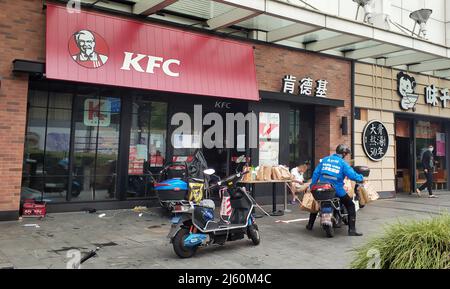 SHANGHAI, CHINA - APRIL 26, 2022 - Deliverymen work at the gate of KFC on April 26, 2022 in Shanghai, China Stock Photo