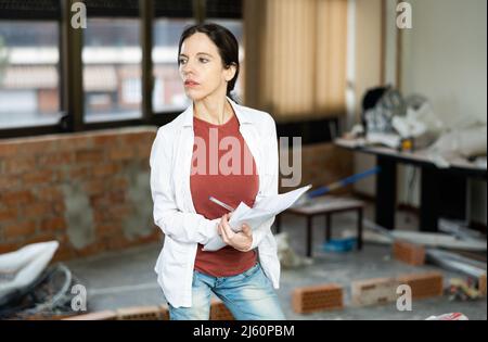 Interested brunette making notes while planning home renovation Stock Photo