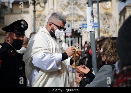 April 26, 2022, Pagani, Salerno, Italy: Pagani, Salerno, Italy - April 24, 2022 : A priest distributes the host during the celebration of Holy Mass in Piazza Bernardo D'Arezzo in honor of Santa Maria Incoronata del Carmine called ''Madonna delle Galline'' The feast of Our Lady of the Hens is a religious and civil event that takes place annually in Pagani (Salerno) from the Friday of the eighth of Easter to the following Monday. The festival, celebrated in the homonymous sanctuary, is organized by the Carmelite Fathers of the sanctuary itself and by the Archconfraternity of Our Lady of the Hens Stock Photo