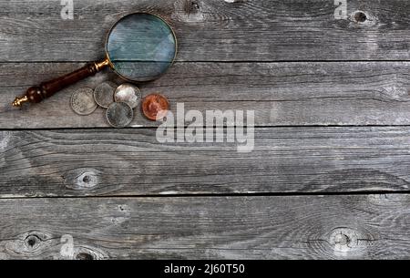 United States collection of vintage historical coins and an antique magnify glass on rustic wood table Stock Photo