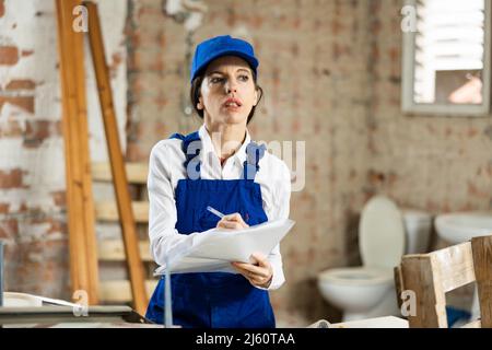 Female foreman making task list during works in building under construction Stock Photo