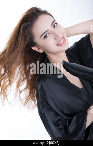 Young and beautiful Chinese woman using a hair dryer to dry hair, on white background - stock photo Stock Photo