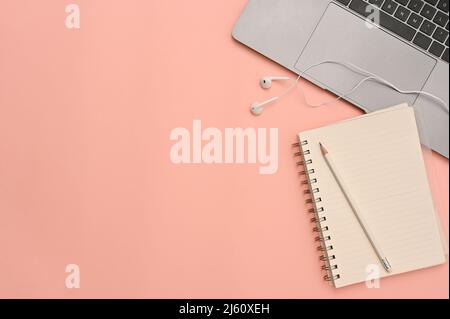 Overhead image, Minimal pastel pink workspace background with laptop computer, earphones, diary, pencil and copy space. Stock Photo