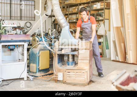 Carpenter working on thicknesser machine in joinery Stock Photo