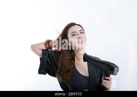 Young and beautiful Chinese woman using a hair dryer to dry hair, on white background - stock photo Stock Photo