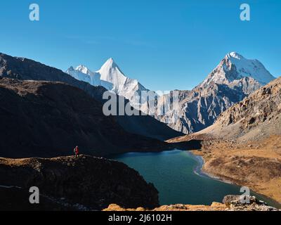 asian hiker looking at mount jampayang, mount chanadorje and lake boyongcuo at sunrise in yading national park, daocheng county, sichuan province, chi Stock Photo
