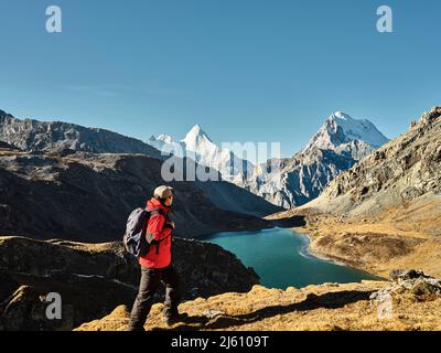 asian hiker looking at mount jampayang, mount chanadorje and lake boyongcuo at sunrise in yading national park, daocheng county, sichuan province, chi Stock Photo