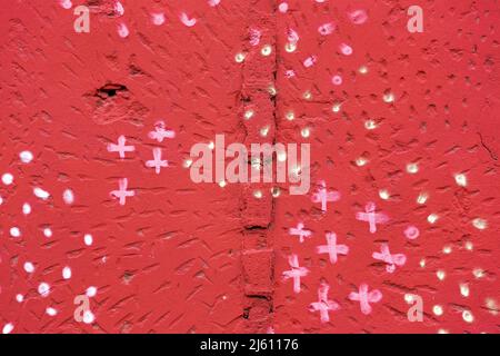 spotted red painted rough plaster wall surface. abstract colorful background. Stock Photo