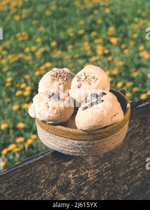 bun from switzerland called buerli decorated with sesame and pumpkin seeds on garden fence in front of flower meadow Stock Photo