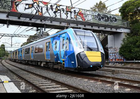 City bound High Capacity Metro Train passing under a footbridge in the inner suburbs of Melbourne on an overcast day Stock Photo