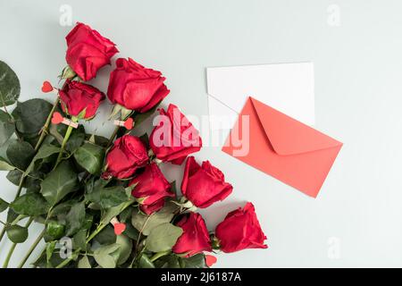 bouquet of red fresh roses and two greeting envelopes on a white background. top view Stock Photo