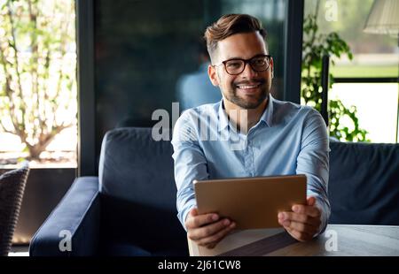 Portrait of young successful businessman with digital device working in corporate business office Stock Photo