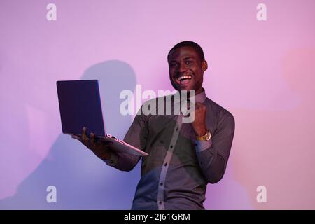 excited african man holding a laptop rejoices Stock Photo