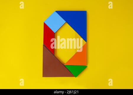 Colorful number 0 made with tangram toy, colored tangram number zero isolated on yellow background, side view of zeroth numeric, kids game idea Stock Photo