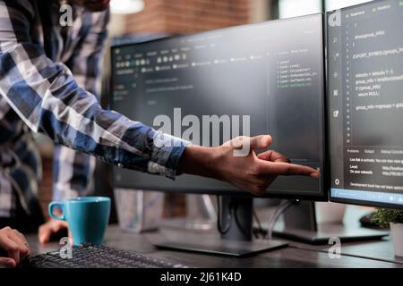 Blockchain engineer pointing out mistake in network security software line code. Cybernetics developers engineering system updates and processing data blocks uploaded by artificial intelligence. Stock Photo