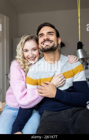 Smiling young couple sitting together at home Stock Photo