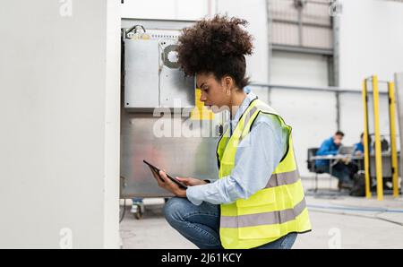 Technician using tablet PC crouching in factory Stock Photo
