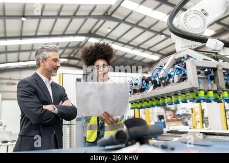 Engineer reading blueprint discussing with businessman in factory Stock Photo