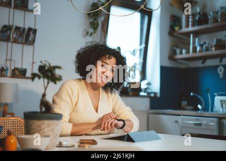 Smiling woman with tablet PC using smart watch at home Stock Photo