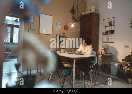Woman using tablet PC at dining table Stock Photo