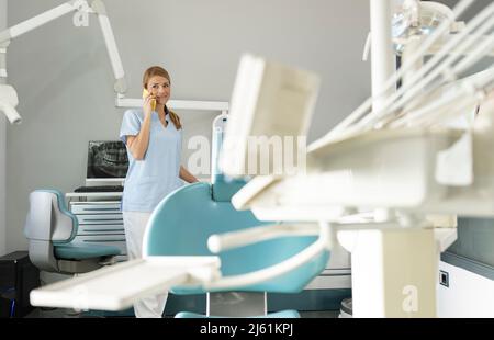 Dentist talking on smart phone at medical clinic Stock Photo