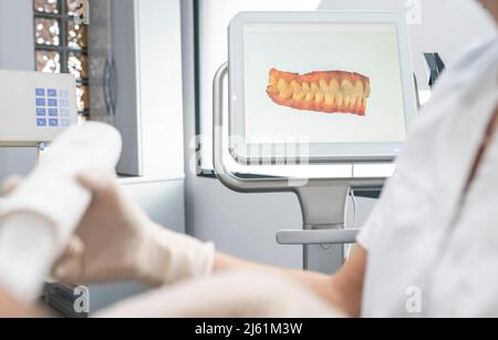Dentist working by scanned image of teeth on monitor screen at dental clinic Stock Photo