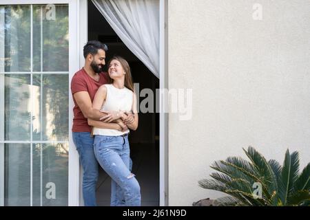 Happy couple looking at each other standing on doorway Stock Photo