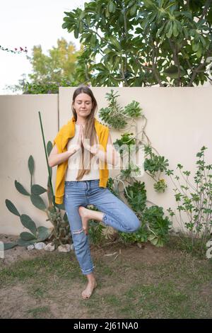 Woman doing tree pose on deck chair near swimming pool Stock Photo - Alamy
