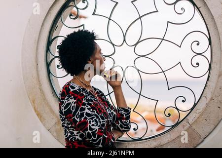Thoughtful woman looking through window Stock Photo