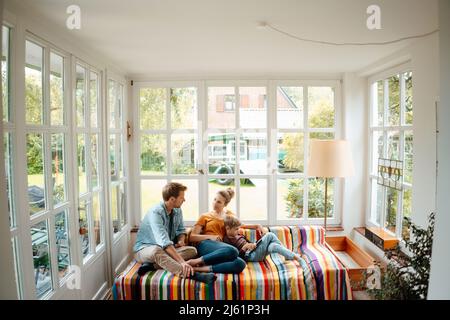 Man and woman talking by son using tablet PC on sofa at home Stock Photo