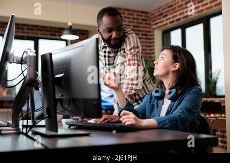 Smiling coworker talking with friendly 3D artist about electronic arts and digital graphics developing. Creative agency diverse employees in brainstorming production ideas. Stock Photo